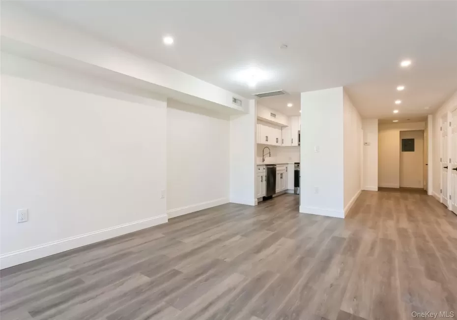 Unfurnished living room with light wood finished floors, visible vents, baseboards, recessed lighting, and a sink Unfurnished living room with light wood finished floors, visible vents, baseboards, recessed lighting, and a sink