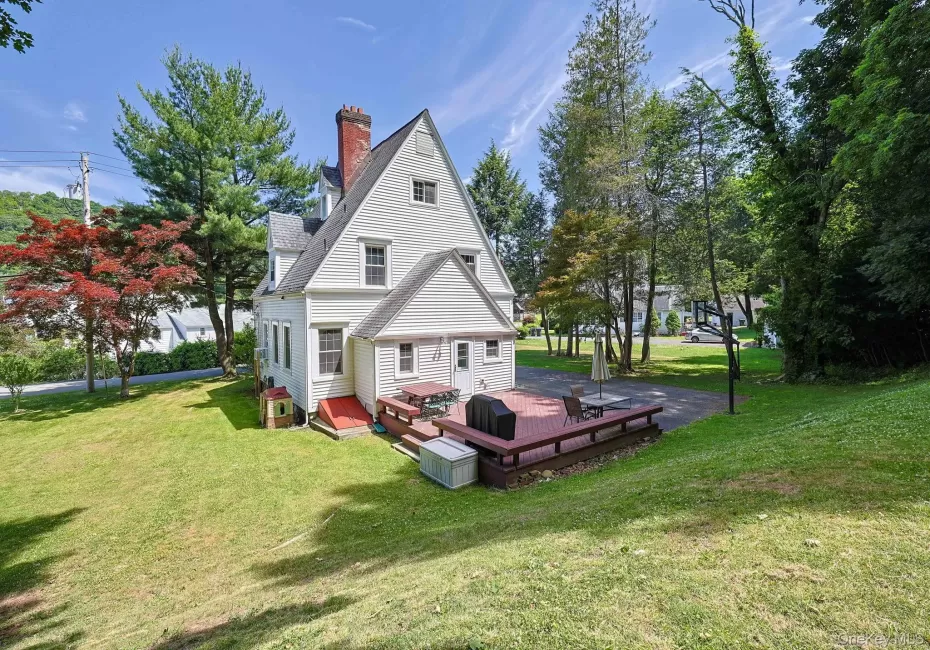 White-sided residence featuring a red brick chimney and a multi-level wood deck White-sided residence featuring a red brick chimney and a multi-level wood deck