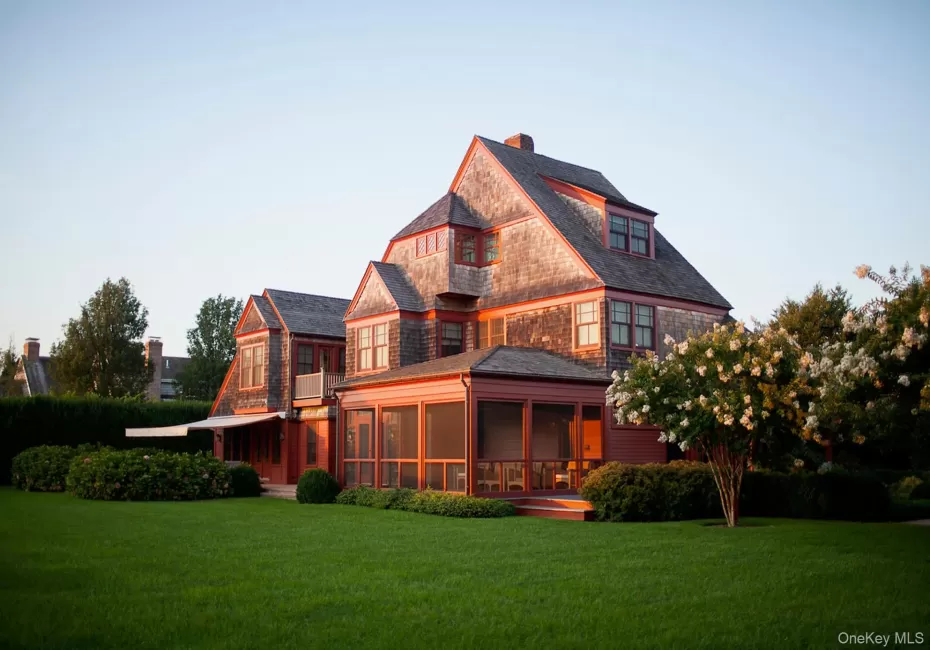 Back of property featuring a sunroom, a lawn, and a chimney Back of property featuring a sunroom, a lawn, and a chimney