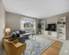 Living room featuring radiator, light tile patterned flooring, and a wall unit AC Living room featuring radiator, light tile patterned flooring, and a wall unit AC