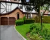 Tudor-style house featuring asphalt driveway, a garage, and a front lawn Tudor-style house featuring asphalt driveway, a garage, and a front lawn
