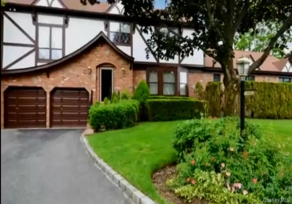 Tudor-style house featuring asphalt driveway, a garage, and a front lawn Tudor-style house featuring asphalt driveway, a garage, and a front lawn