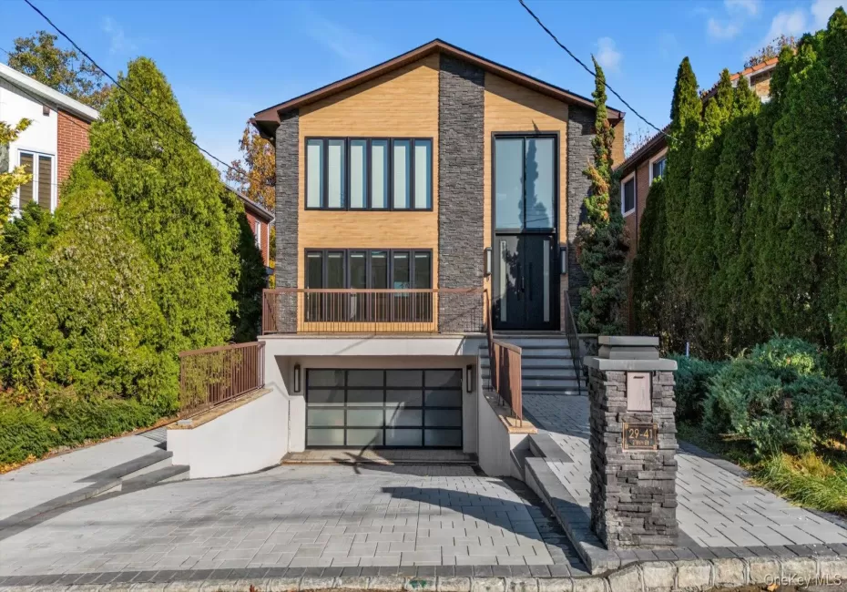 Modern home with decorative driveway, an attached garage, and stone siding Modern home with decorative driveway, an attached garage, and stone siding