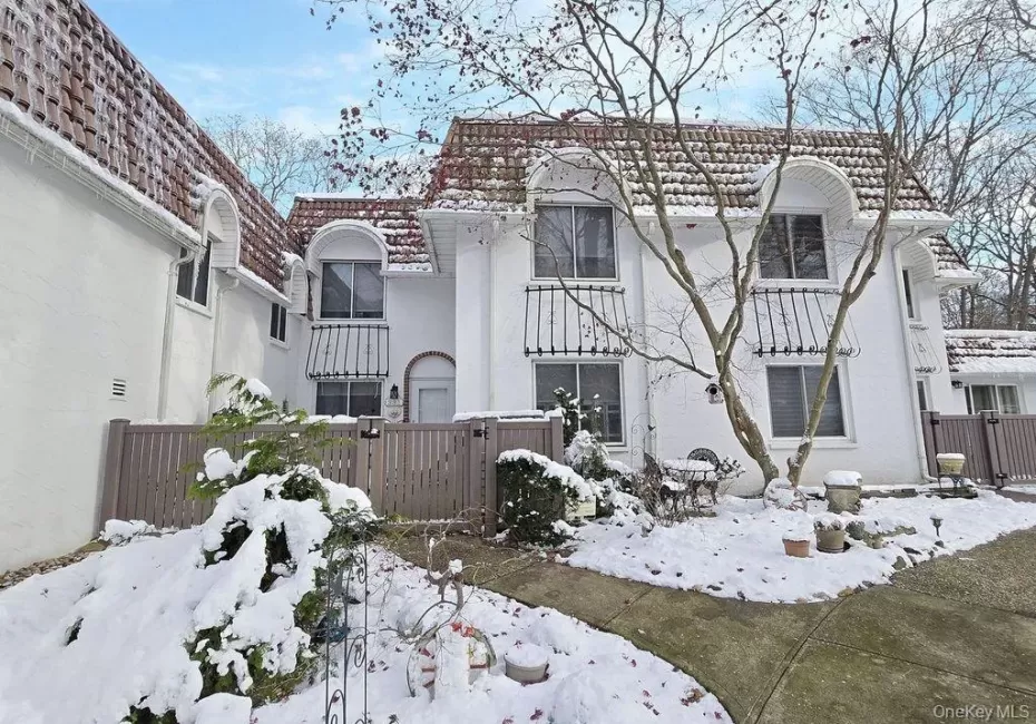 Snow covered house featuring stucco siding and a tiled roof Snow covered house featuring stucco siding and a tiled roof