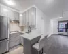 Kitchen with gray cabinetry, stainless steel appliances, tasteful backsplash, and a breakfast bar Kitchen with gray cabinetry, stainless steel appliances, tasteful backsplash, and a breakfast bar
