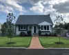 Charming residence featuring a light gray exterior, dark gray shingle roof, and a red brick paver walkway leading to the front entry Charming residence featuring a light gray exterior, dark gray shingle roof, and a red brick paver walkway leading to the front entry