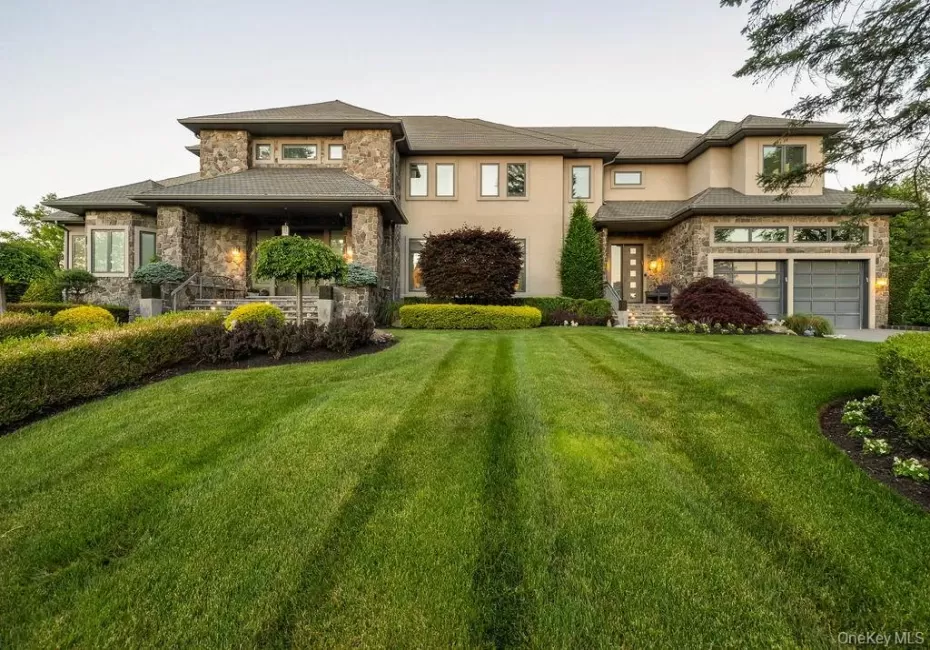 Stately multi-level residence featuring a stone and stucco facade, a prominent covered entry, and a two-car garage with frosted glass panels Stately multi-level residence featuring a stone and stucco facade, a prominent covered entry, and a two-car garage with frosted glass panels