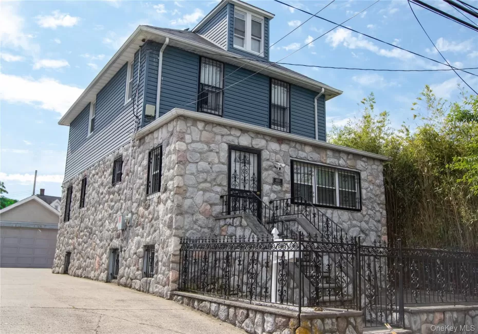 Stone and siding exterior with wrought iron railing, concrete stairs, and security bars Stone and siding exterior with wrought iron railing, concrete stairs, and security bars