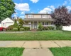 Traditional-style house featuring a porch, a chimney, a front yard, and a garage Traditional-style house featuring a porch, a chimney, a front yard, and a garage