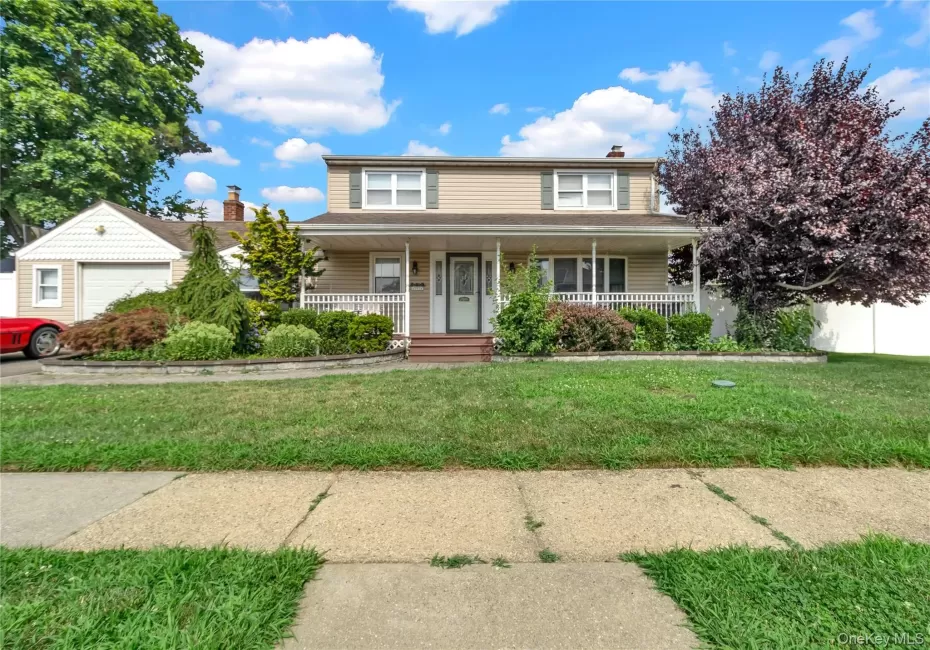 Traditional-style house featuring a porch, a chimney, a front yard, and a garage Traditional-style house featuring a porch, a chimney, a front yard, and a garage