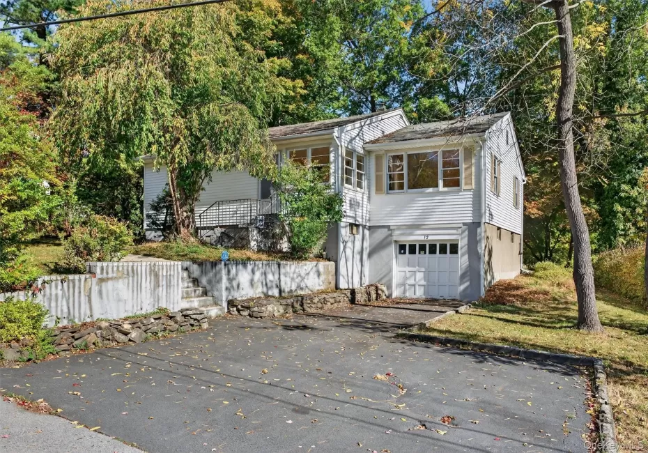 View of front of home featuring asphalt driveway, a garage, and view of wooded area View of front of home featuring asphalt driveway, a garage, and view of wooded area