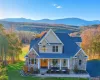 View of front of house with stone siding, covered porch, a chimney, a forest view, and a front yard View of front of house with stone siding, covered porch, a chimney, a forest view, and a front yard