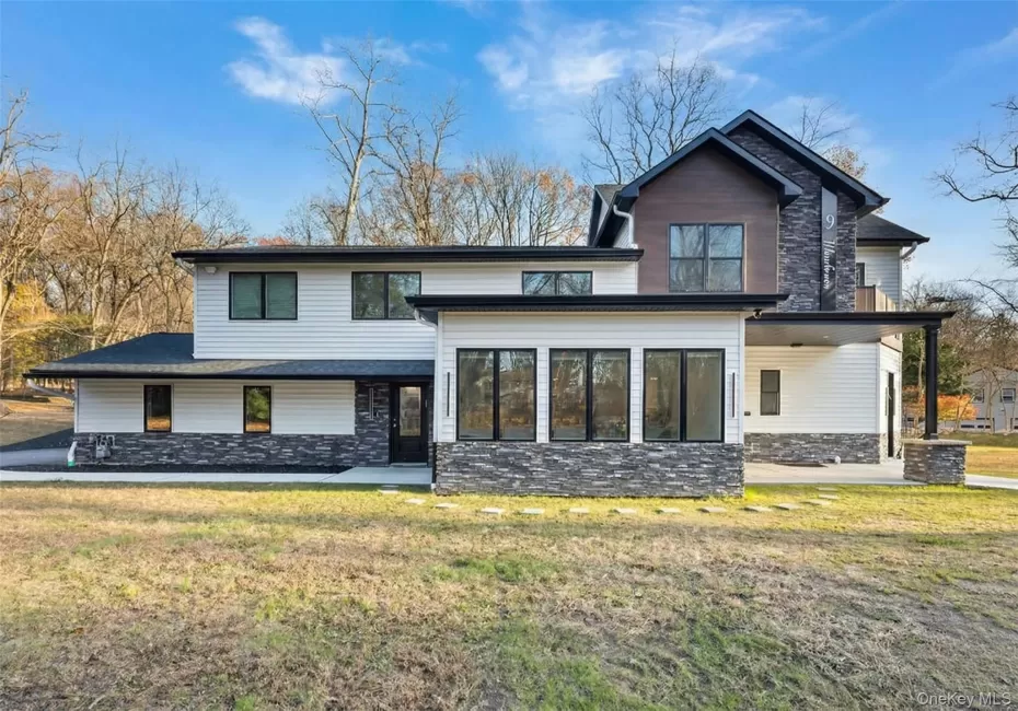 View of front of house featuring stone siding, a patio area, and a front yard View of front of house featuring stone siding, a patio area, and a front yard
