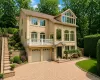 Stucco exterior with multiple arched windows, prominent balcony with white railing, and an expansive paved driveway Stucco exterior with multiple arched windows, prominent balcony with white railing, and an expansive paved driveway
