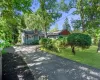 Paved driveway leading to a residence featuring blue siding and red shutters Paved driveway leading to a residence featuring blue siding and red shutters