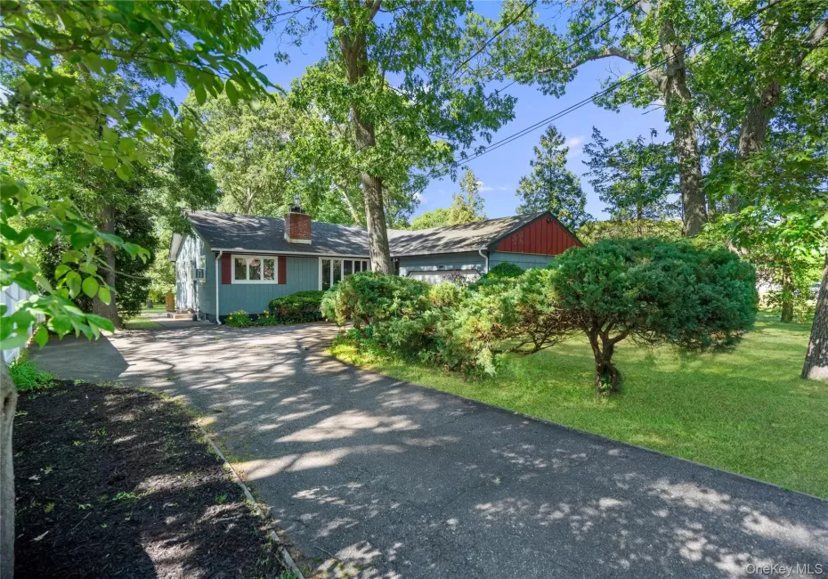 Paved driveway leading to a residence featuring blue siding and red shutters Paved driveway leading to a residence featuring blue siding and red shutters