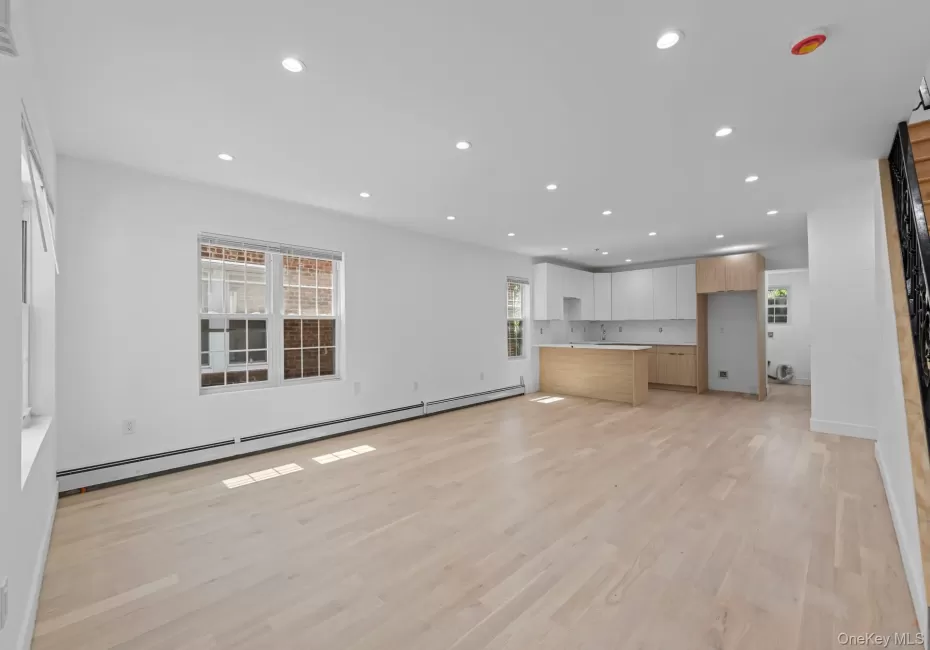 Open-concept living space featuring light wood-finish flooring, recessed lighting, and white baseboards Open-concept living space featuring light wood-finish flooring, recessed lighting, and white baseboards