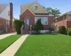 Brick and shingle exterior featuring a prominent front lawn, concrete pathway, and a paved driveway Brick and shingle exterior featuring a prominent front lawn, concrete pathway, and a paved driveway