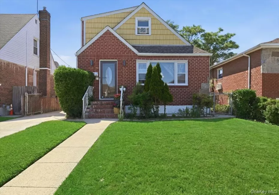Brick and shingle exterior featuring a prominent front lawn, concrete pathway, and a paved driveway Brick and shingle exterior featuring a prominent front lawn, concrete pathway, and a paved driveway