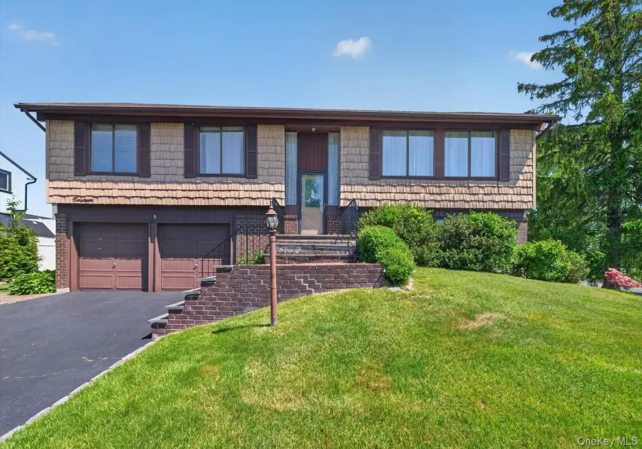 Split-level home featuring cedar shake siding and a brown trim Split-level home featuring cedar shake siding and a brown trim