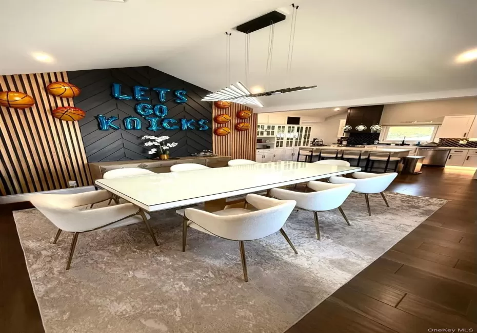 Open-concept dining area featuring dark wood-finish flooring, a modern linear chandelier, and a vaulted ceiling Open-concept dining area featuring dark wood-finish flooring, a modern linear chandelier, and a vaulted ceiling