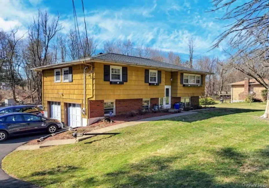Split-level residence featuring yellow siding and black louvered shutters Split-level residence featuring yellow siding and black louvered shutters