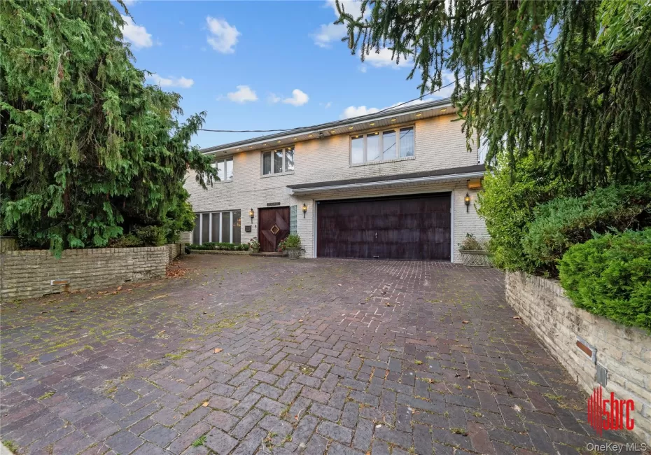 View of front of property featuring decorative driveway, brick siding, and a garage View of front of property featuring decorative driveway, brick siding, and a garage