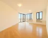 Unfurnished room with light wood-style flooring, a wall of windows, and a wall mounted air conditioner Unfurnished room with light wood-style flooring, a wall of windows, and a wall mounted air conditioner