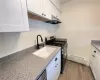 Kitchen featuring white shaker-style cabinetry, speckled countertops, a matte black gooseneck faucet, a stainless steel range, and wood-finish flooring Kitchen featuring white shaker-style cabinetry, speckled countertops, a matte black gooseneck faucet, a stainless steel range, and wood-finish flooring