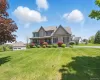 View of front facade featuring a front lawn, stone siding, and a porch View of front facade featuring a front lawn, stone siding, and a porch