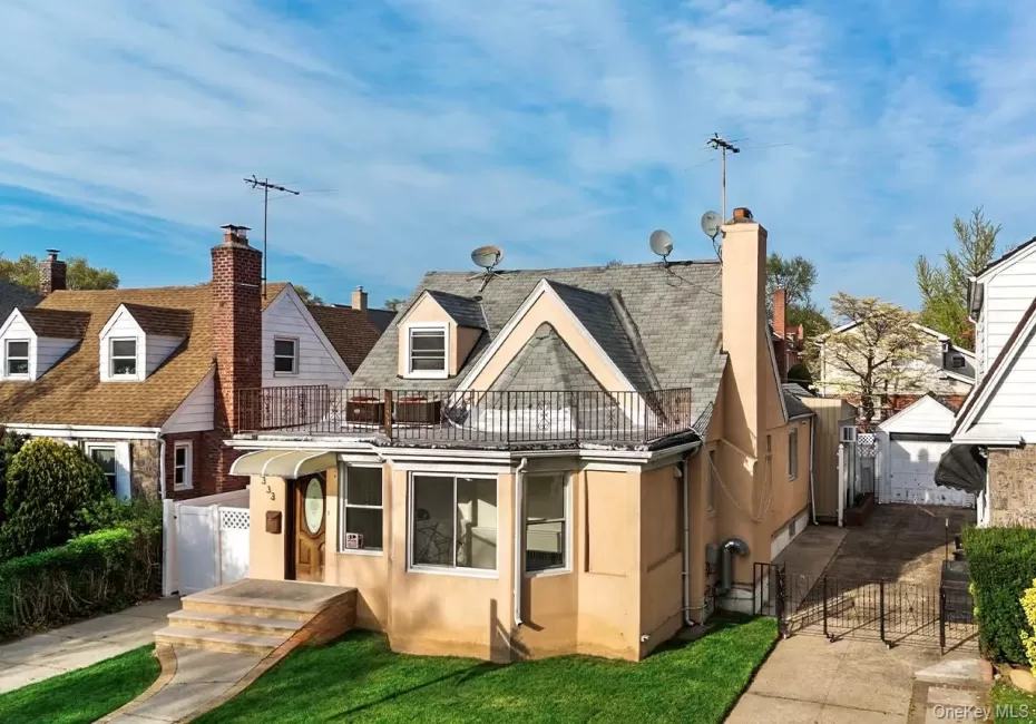 Front view of house with a chimney, fence, a balcony, and stucco siding Front view of house with a chimney, fence, a balcony, and stucco siding