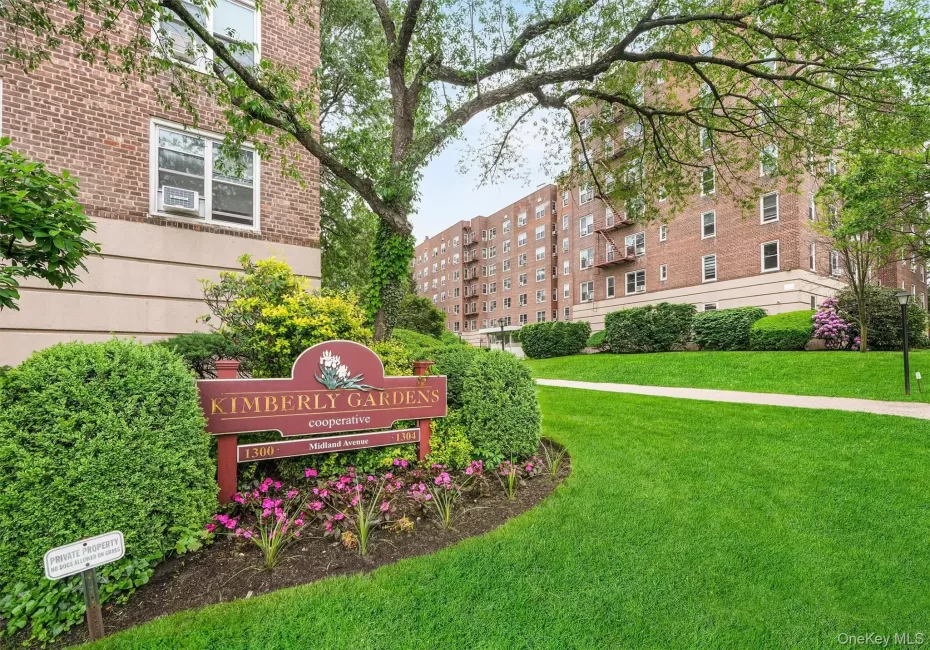 Landscaped entry featuring a 'Kimberly Gardens' sign, manicured shrubs, and vibrant floral plantings Landscaped entry featuring a 'Kimberly Gardens' sign, manicured shrubs, and vibrant floral plantings