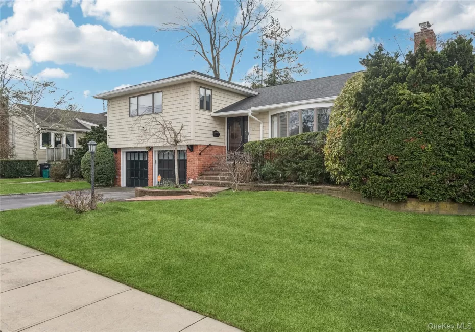 Tri-level home with brick siding, driveway, a front yard, and an attached garage Tri-level home with brick siding, driveway, a front yard, and an attached garage