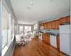 Kitchen and living room featuring white appliances, wood finished floors, brown cabinetry, open floor plan, and dark stone countertops Kitchen and living room featuring white appliances, wood finished floors, brown cabinetry, open floor plan, and dark stone countertops
