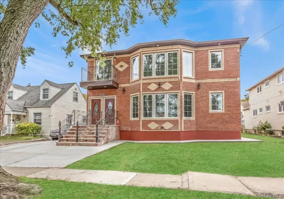 View of front facade with brick siding, a balcony, and a front lawn View of front facade with brick siding, a balcony, and a front lawn