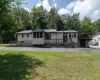 Back of house featuring a deck, a yard, view of scattered trees, and driveway Back of house featuring a deck, a yard, view of scattered trees, and driveway