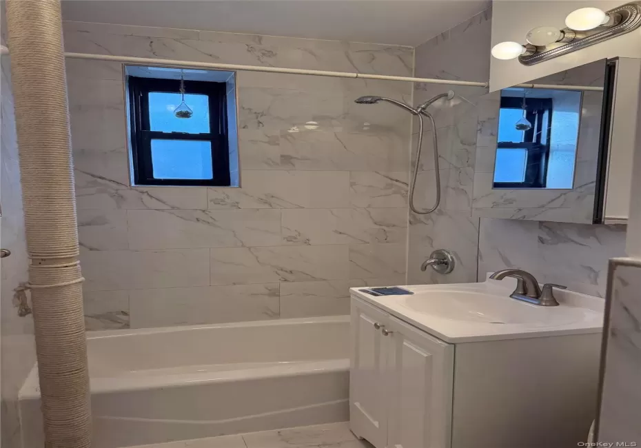 Bathroom featuring a white subway tile surround with subtle veining, complete with a white bathtub, and brushed nickel shower fixtures Bathroom featuring a white subway tile surround with subtle veining, complete with a white bathtub, and brushed nickel shower fixtures