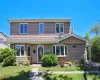 Two-story residence featuring tan shingle siding and a prominent bay window Two-story residence featuring tan shingle siding and a prominent bay window