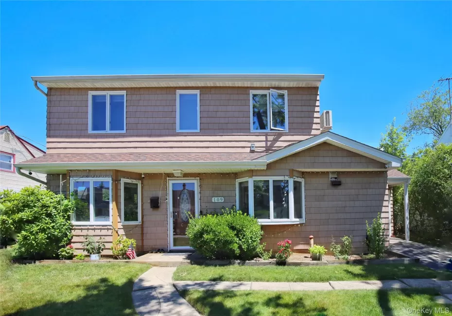 Two-story residence featuring tan shingle siding and a prominent bay window Two-story residence featuring tan shingle siding and a prominent bay window