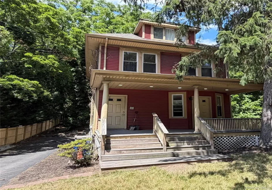Red siding exterior featuring a covered porch, white trim, and a dormer window Red siding exterior featuring a covered porch, white trim, and a dormer window