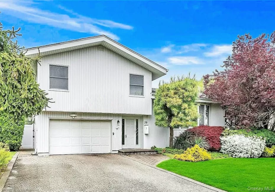 Split-level residence featuring white siding, a two-car garage, and a paver stone front walk Split-level residence featuring white siding, a two-car garage, and a paver stone front walk