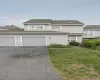 Light gray-sided townhouse with dual garage doors and an asphalt driveway Light gray-sided townhouse with dual garage doors and an asphalt driveway