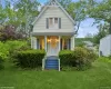 View of front facade with a chimney, a porch, a front lawn, and roof with shingles View of front facade with a chimney, a porch, a front lawn, and roof with shingles