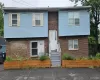 Two-story building featuring brick and light blue siding, a central entrance with a white door, and gray steps Two-story building featuring brick and light blue siding, a central entrance with a white door, and gray steps