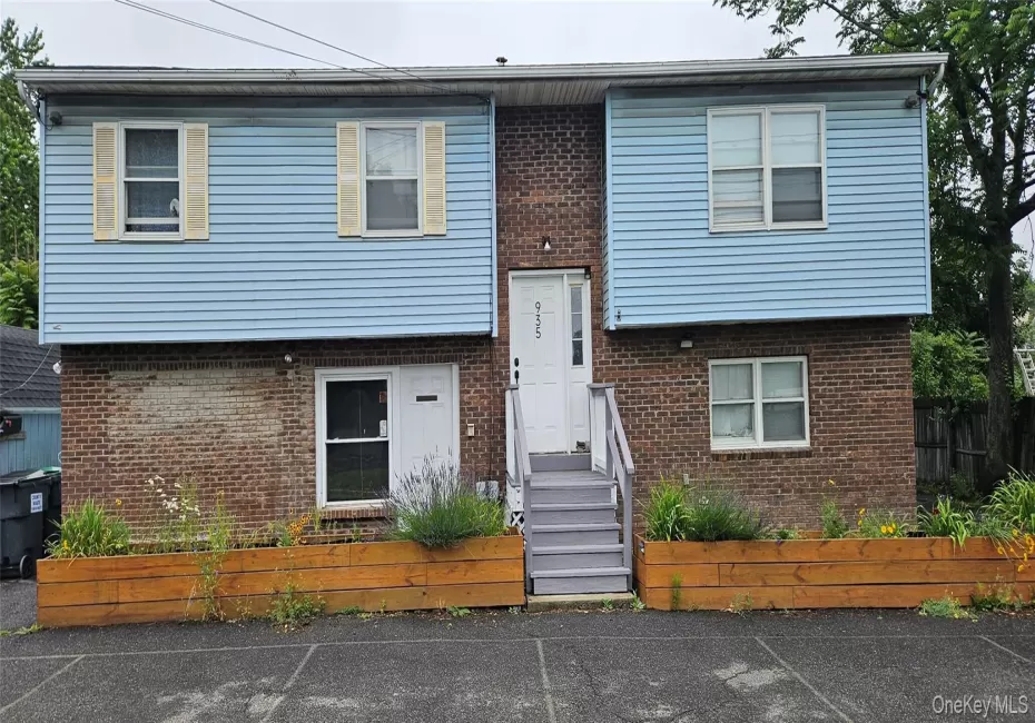 Two-story building featuring brick and light blue siding, a central entrance with a white door, and gray steps Two-story building featuring brick and light blue siding, a central entrance with a white door, and gray steps