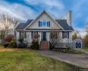View of front of property with an outdoor structure, a front lawn, a chimney, and roof with shingles View of front of property with an outdoor structure, a front lawn, a chimney, and roof with shingles