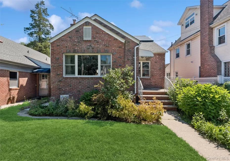 Brick exterior with a gabled roofline, multiple windows, and a paved walkway leading to the entrance Brick exterior with a gabled roofline, multiple windows, and a paved walkway leading to the entrance