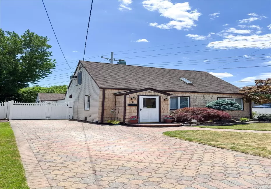 Exterior featuring shingle siding, a multi-tone paver driveway, and a fenced yard Exterior featuring shingle siding, a multi-tone paver driveway, and a fenced yard