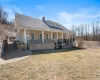 Back of property with a shingled roof, covered porch, a chimney, and a lawn Back of property with a shingled roof, covered porch, a chimney, and a lawn