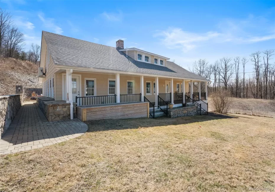 Back of property with a shingled roof, covered porch, a chimney, and a lawn Back of property with a shingled roof, covered porch, a chimney, and a lawn